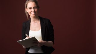 ノートとペンを手に持ってメモをする外国人女性